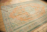 Vintage distressed Oushak rug with faded terra cotta, blues, and green tones; even wear visible.