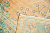 Distressed apricot Oushak carpet pile folded back, showing light foundation and intact selvage.