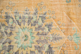 Distressed Oushak rug detail: faded apricot, mint, and visible light foundation.