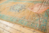 Distressed vintage Oushak rug corner, intricate mint green border and faded apricot field motifs.