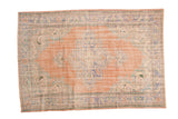 Distressed Oushak rug with faded blush rose field and elongated dusty blue medallion.