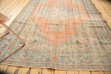 Distressed Oushak rug corner with European rococo scrolling and worn pile texture.