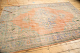 Corner of vintage distressed Oushak carpet, rococo spandrel, even wear, blush rose, dusty blue.