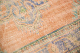 Distressed Oushak carpet's worn pile texture with blush, dusty blue, and mint green scrolling.