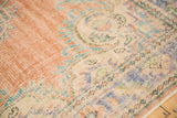 Distressed Oushak with even wear, featuring pale blush rose field and European rococo spandrel.