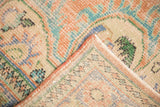 Detail of vintage Oushak rug corner showing worn pile, light foundation, original orange selvage, and muted tones.