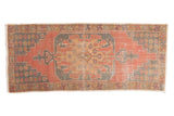 Distressed vintage Oushak runner with geometric medallion, faded cinnabar red and denim blue.