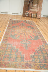 Distressed vintage Oushak rug corner: starburst spandrel, serpent border, geometric patterns in soft cinnabar, blue, gold.