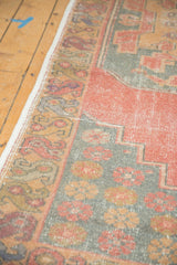 Distressed vintage Oushak rug runner showing faded cinnabar red field and serpent motif border.