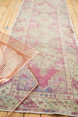 A vintage Turkish Oushak runner's time-softened colors and distressed geometric pattern.