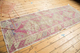 Angled full-length view of a distressed Turkish Oushak runner with a decorative, low-pile patina.