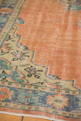 Close-up of distressed apricot field with dusty mint green border, showing even wear.