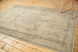 Distressed vintage Oushak carpet corner, faded ivory and platinum with worn vinery and fringe.