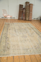 Corner of distressed Oushak rug, showcasing faded antique ivory and textural wear.