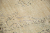 Close-up of distressed Oushak rug, showing worn antique ivory pile and light foundation.