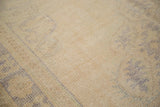 Texture of a distressed vintage Oushak rug, featuring soft ivory and muted pale denim blue tones.