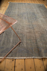 Distressed Oushak rug showing textured dark grey pile, lazy lines, subtle blue, and fringe.