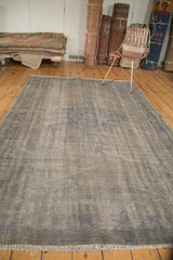 Distressed Oushak carpet edge highlighting worn grey pile, subtle blue tones, and 