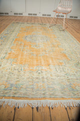 Distressed vintage Oushak rug's ivory fringe and worn pale orange, slate blue motifs.