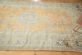Distressed pale burnt orange field, worn floral motifs, and multi-color patterned border on vintage Oushak.