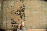 Distressed Oushak rug showing bold charcoal geometric medallion and time-softened sand tones.