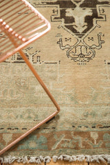 Distressed Oushak rug with muted brown, slate blue border and sand colored fringe.