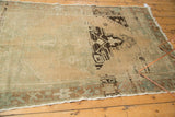 Distressed Oushak rug corner, showing geometric medallion outline and contrasting border.