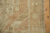 Distressed Oushak rug pile shows stepped pattern in faded sand, beige, and bronze tones.