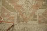 Distressed short pile of a vintage Oushak rug in faded bronze, sand, and ivory.