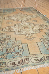 Distressed Oushak rug corner showing geometric spandrel, pale blue, sand, and exposed knot heads.