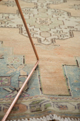 Distressed Oushak rug close-up, revealing low pile texture and muted geometric patterns in beige and blue.