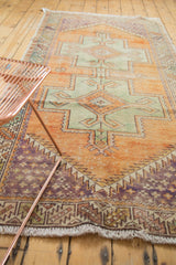 Distressed vintage Oushak rug, geometric field, boteh motifs, rust, green, and royal purple.