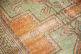 Distressed vintage Oushak rug with glossy pale rust terra cotta and copper green geometric pattern.