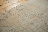 Muted ivory and peach tones on distressed Oushak rug showing abrash and worn knot heads.