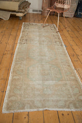 Distressed Oushak runner corner with worn pile, secured side, and antique ivory fringe.