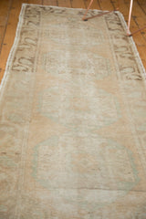 Distressed Oushak runner with abrash, highlighting faded peach and mint medallion motifs.