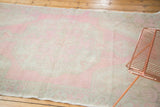 Distressed Oushak rug's low pile, faded pale pink and antique ivory floral patterns.