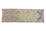 Distressed Oushak runner with repeating hook and latch medallions in gem-like blush red, mint, and sky blue.