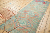 Angled view of a distressed Oushak runner showing its repeating medallions and faded gem-like tones.