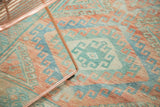 Close-up of the distressed Oushak's short pile showing geometric hook and latch motifs in soft red and blue.