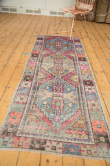 Distressed pink, blue, and ivory patterns with intact selvage on a vintage Oushak runner.