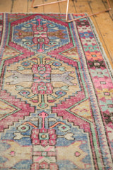 Close-up of distressed Oushak rug texture, showing short pile and vivid pink, pale blue, ivory stepped motifs.