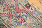Vintage distressed Oushak runner displays textured pink, blue, and ivory stepped motifs.