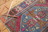 Distressed Oushak runner close-up of pink, blue, and ivory stepped geometric pattern with fringe.