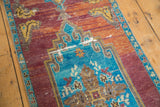 Distressed vintage Oushak runner detail: sky blue medallion, worn orange-red field, low pile.