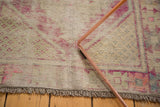 Distressed Oushak rug pile with visible foundation, plum pink hues, and delicate fringe.
