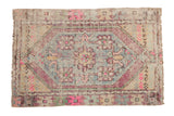 Distressed Oushak rug with slate blue medallion, aubergine field, and pink floral patterns.