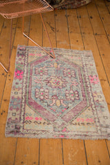 Distressed Oushak rug corner showing pink, aubergine serpent motif with mostly even wear.