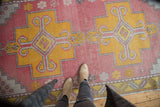 Distressed Oushak runner detail: geometric saffron yellow, raspberry red, and visible low pile.