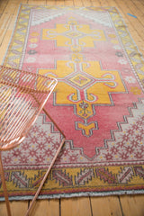 Vintage Oushak rug's geometric pattern in distressed pale raspberry and saffron yellow.